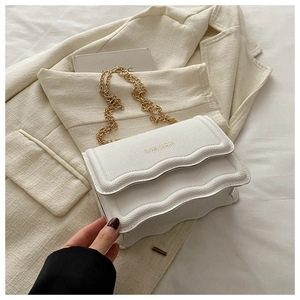 Macro shot of white lychee grain crossbody bag with wavy edges and gold FASHION logo