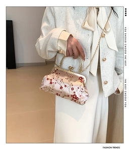 Detail of red plum blossom embroidery on a beige silk kiss-lock clutch with chain