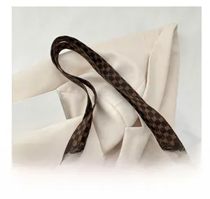 Gros plan sur les poignées marron à motif géométrique d'un sac cabas élégant en toile
