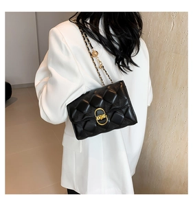 Close-up of black quilted shoulder bag with gold chain strap and turn-lock closure