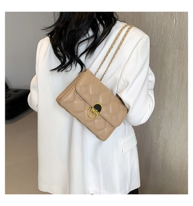 Detail of khaki quilted chain crossbody bag showing metal lock and leather texture