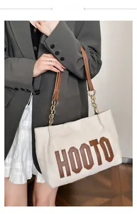 Detail of beige tote bag with brown HOOTO lettering and leather chain straps