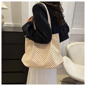 Détail d'un grand sac cabas à monogramme porté par un mannequin dans un décor intérieur