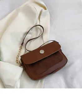 Detail of brown leather and suede crossbody bag with gold chain and metal buckle