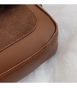 Detailed close-up of brown lychee grain leather and suede stitching on shoulder bag