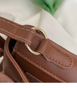 Close-up of premium gold-tone metal hardware and stitching on brown leather handbag