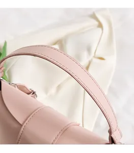 Detail of soft pink bucket bag handle with reinforced stitching on leather surface