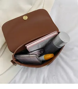 Interior view showing spacious capacity of the brown shoulder bag with cosmetics