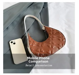 Size comparison between a brown clover-embossed hobo shoulder bag and a smartphone