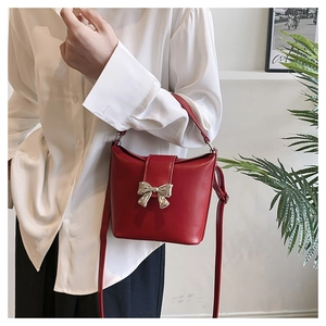 Detail of red PU leather bucket bag with silver metal bow and magnetic closure