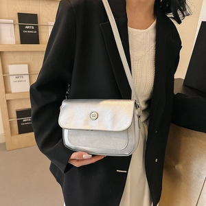 Silver metallic crossbody bag with glitter finish and round buckle shown on a model