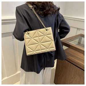 Detail der beigen gesteppten Tasche mit goldener Kette und geometrischem Dreiecksmuster