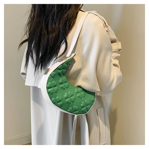 Detail view of crescent shoulder bag featuring green clover embossing and white trim