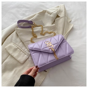 Detailed view of lilac quilted shoulder bag with gold CSS logo and tassel ornament