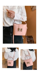 Detailed close-up of a pink bucket bag with a golden bow buckle on a soft brown background