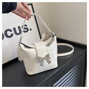 Detail of white matte PU leather bucket bag with silver metal bow and shoulder strap