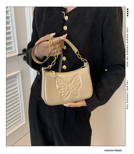 Detail of beige glossy underarm bag with 3D butterfly relief and gold chain strap