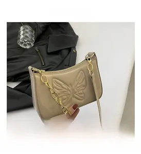Detail of glossy beige patent leather bag featuring an embossed butterfly pattern
