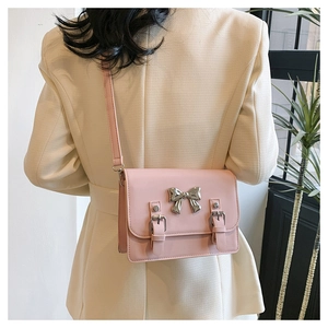 Detail of pink crossbody bag with silver metal bow and double strap decor