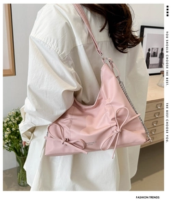 Dettaglio borsa a spalla in pelle rosa con fiocchi decorativi e catena argentata