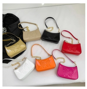 Flat lay view of assorted colorful patent leather shoulder bags with butterfly embossing