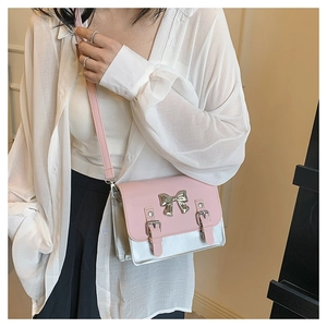 Pink and silver contrast small square crossbody bag with bow buckle on a female model