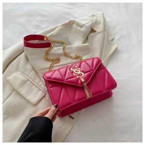 Detailed shot of hot pink quilted crossbody bag featuring a golden S logo and fringe