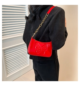 Close-up of a red patent leather underarm bag with butterfly emboss and gold chain