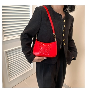 Close-up of red patent leather shoulder bag with embossed butterfly pattern detail