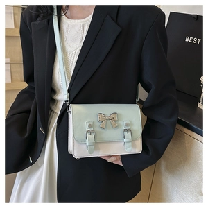 Detail view of mint green and white crossbody bag with a silver bow and metal accents