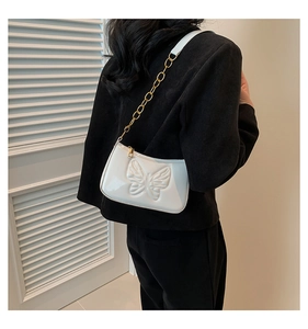Side view of a white patent leather baguette bag with butterfly relief and chain strap