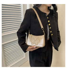 Detail showing the embossed butterfly pattern on the beige patent leather shoulder bag