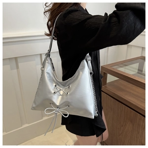 Detailed close-up of a silver PU tote bag featuring a metallic finish and bow ribbon accents