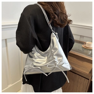 Vue d'épaule d'un sac cabas argenté brillant avec des nœuds et des détails de chaîne chic