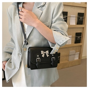 Detailed view of a black crossbody bag with silver bow accent and buckle closure