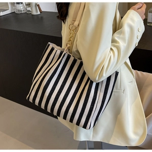 Detail of canvas striped tote with leather straps and gold chain link hardware