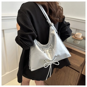 Detail of silver metallic tote bag with decorative cross lacing and chic bow design