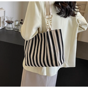 Close-up of black and white striped canvas tote bag with metal chain and leather strap