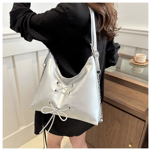 Detail of silver hobo bag featuring lace-up bow decoration and metal chain accents