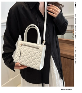 Close-up of a white woven handbag featuring a tassel zipper and elegant top handle