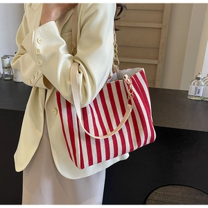 Detail of red and white striped tote bag with leather straps and gold metal chain