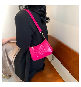 Detail of fuchsia handbag with butterfly embossed pattern and glossy patent leather finish