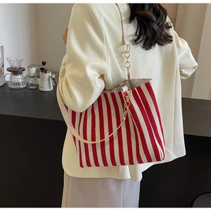Detail of red and white striped canvas tote bag with gold chain and leather strap