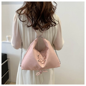 Detail of pink soft PU tote bag with decorative lace-up bow and silver chain strap