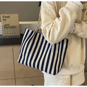 Detail of blue and white striped canvas tote bag with gold chain strap for daily commute