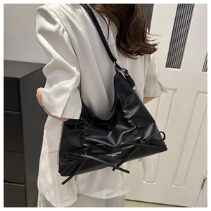 Dettaglio della borsa nera con coulisse, fiocchi in pelle e tracolla a catena d'argento