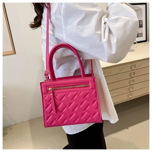 Detail showing bright rose pink quilted handbag with leather pullers and top handle