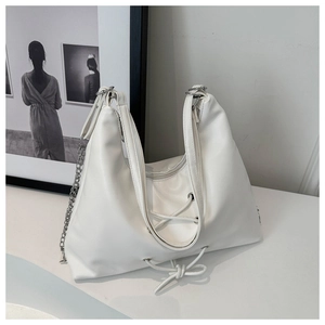 Detail of white PU leather tote featuring lace-up bow design and metallic chain strap