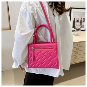 Close-up of hot pink quilted handbag with zipper pocket and woven texture on model