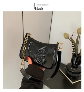Detail of black patent leather shoulder bag featuring embossed butterfly and gold chain